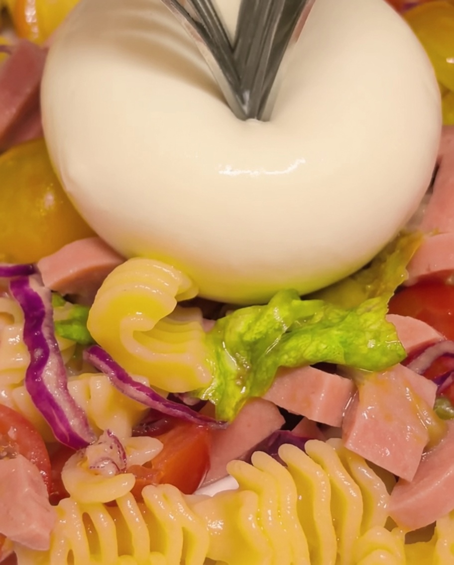Une boule de burrata ouverte à laide dune fourchette pour révéler son cœur crémeux et coulant.