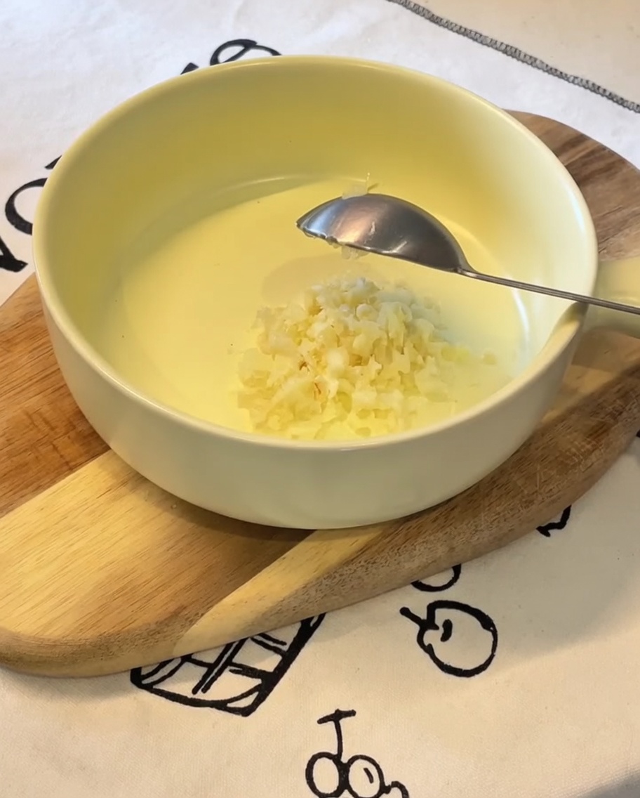 Ail haché, oignons verts, mayonnaise japonaise, jaune dœuf et sachet dassaisonnement ramen dans un bol jaune.