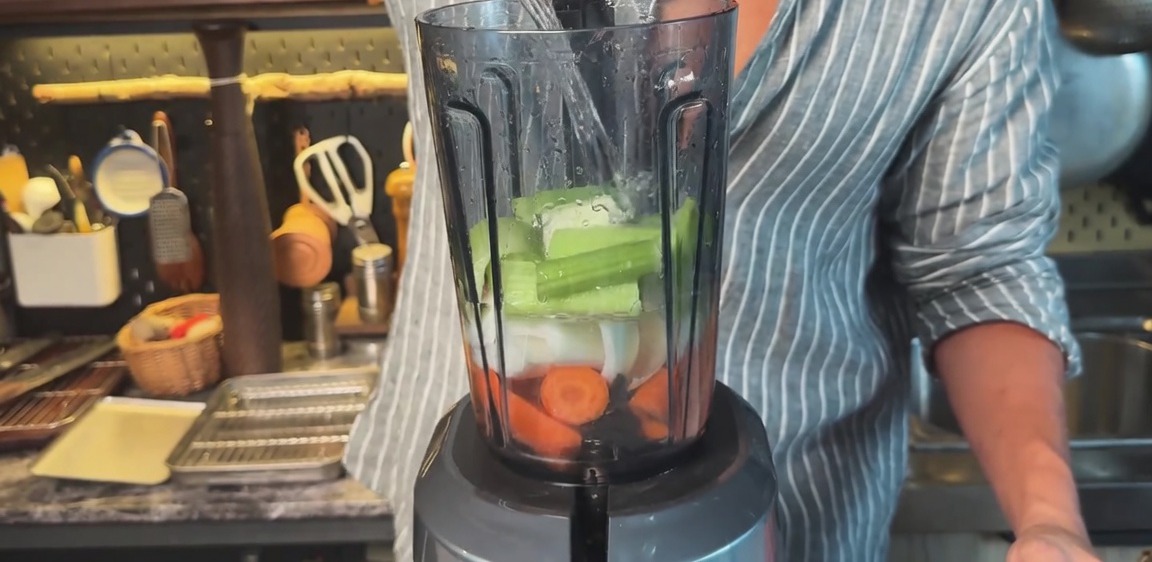 Verser de leau dans un blender rempli de carottes, doignons et de céleri hachés.