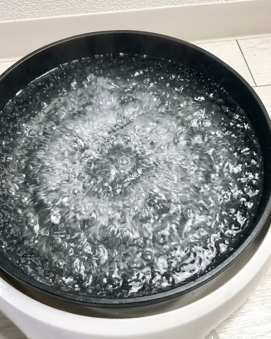 Quatre œufs crus plongés dans une casserole deau bouillante.