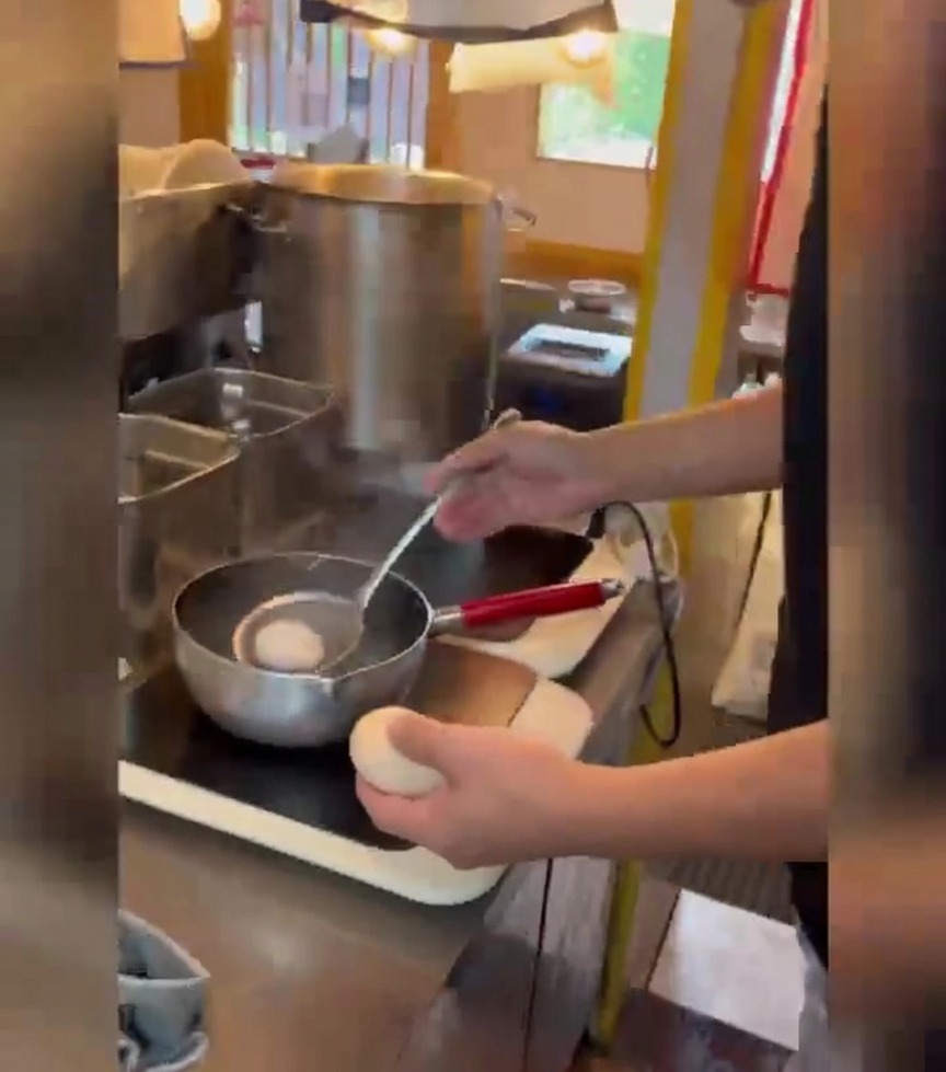 Une personne utilise une écumoire pour déposer délicatement les œufs dans une casserole deau bouillante.