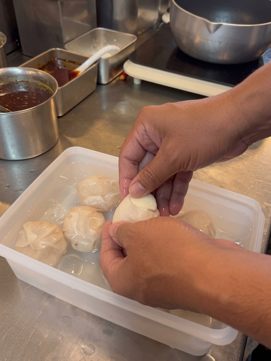 Mains écalant soigneusement un œuf mollet dans un récipient deau froide.