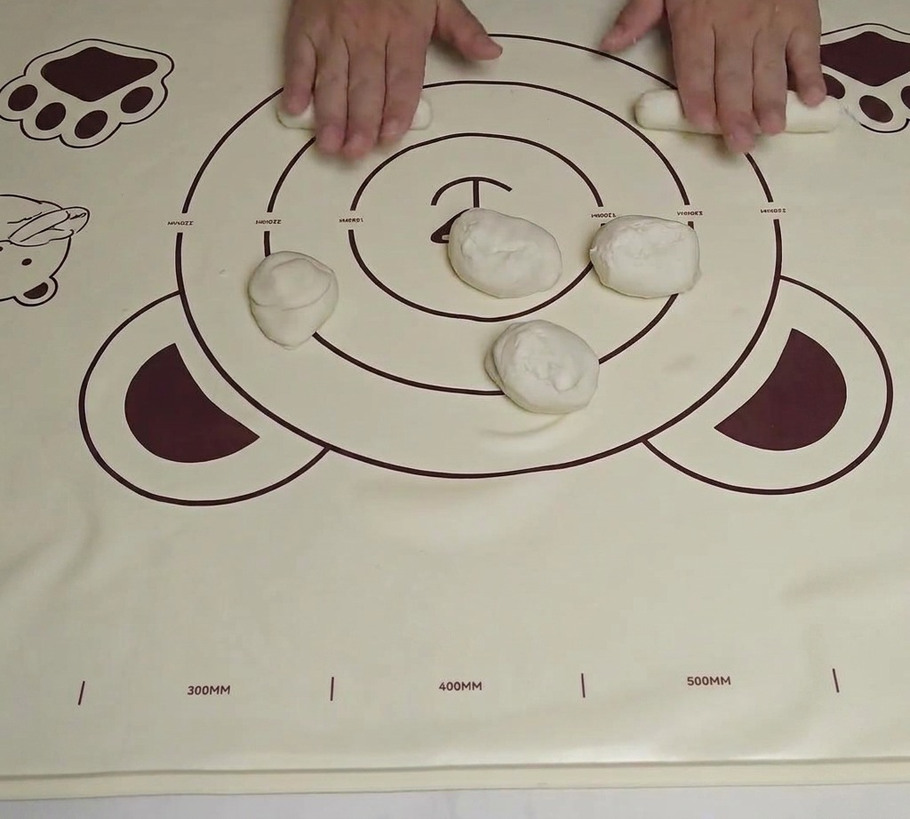 Un morceau de pâte façonné en un court cylindre épais sur un tapis de roulage en silicone.