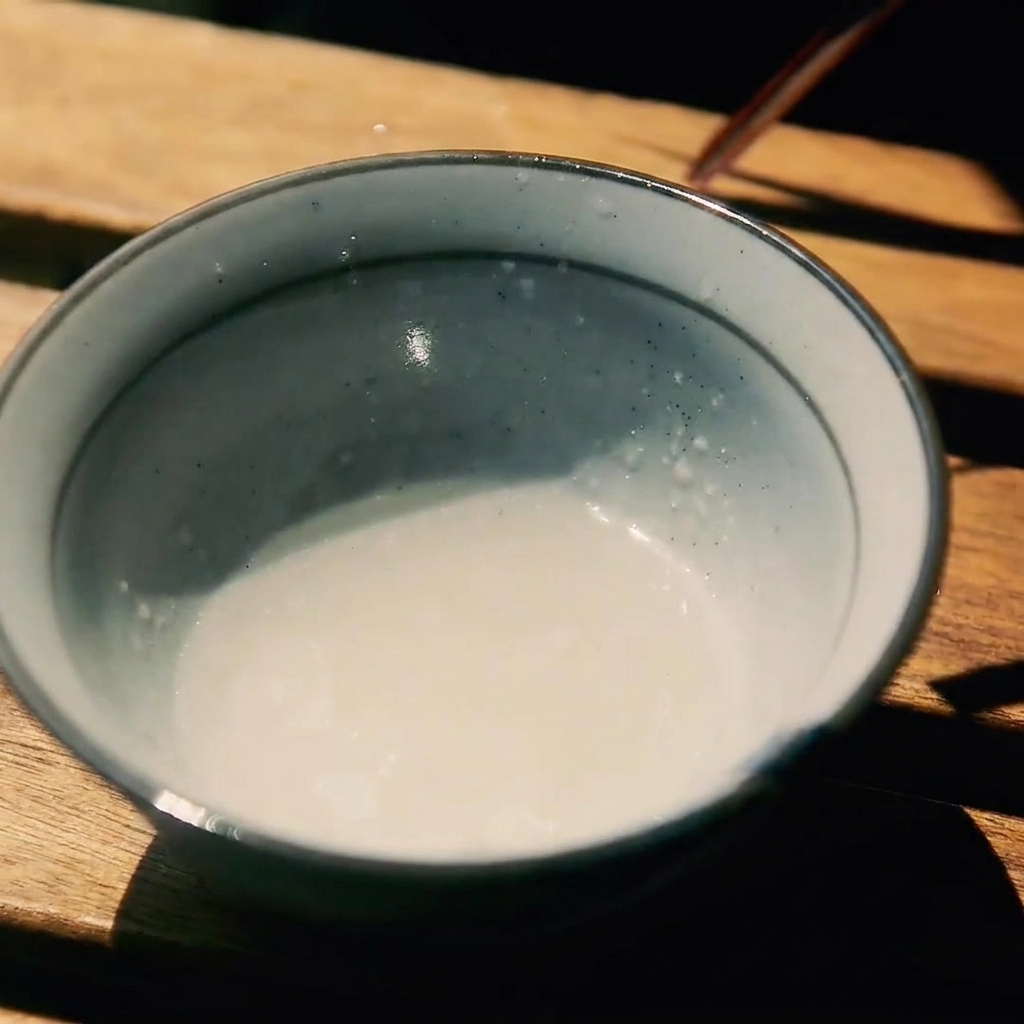 Un petit bol en céramique contenant un mélange de saké, de sucre et de sauce soja.