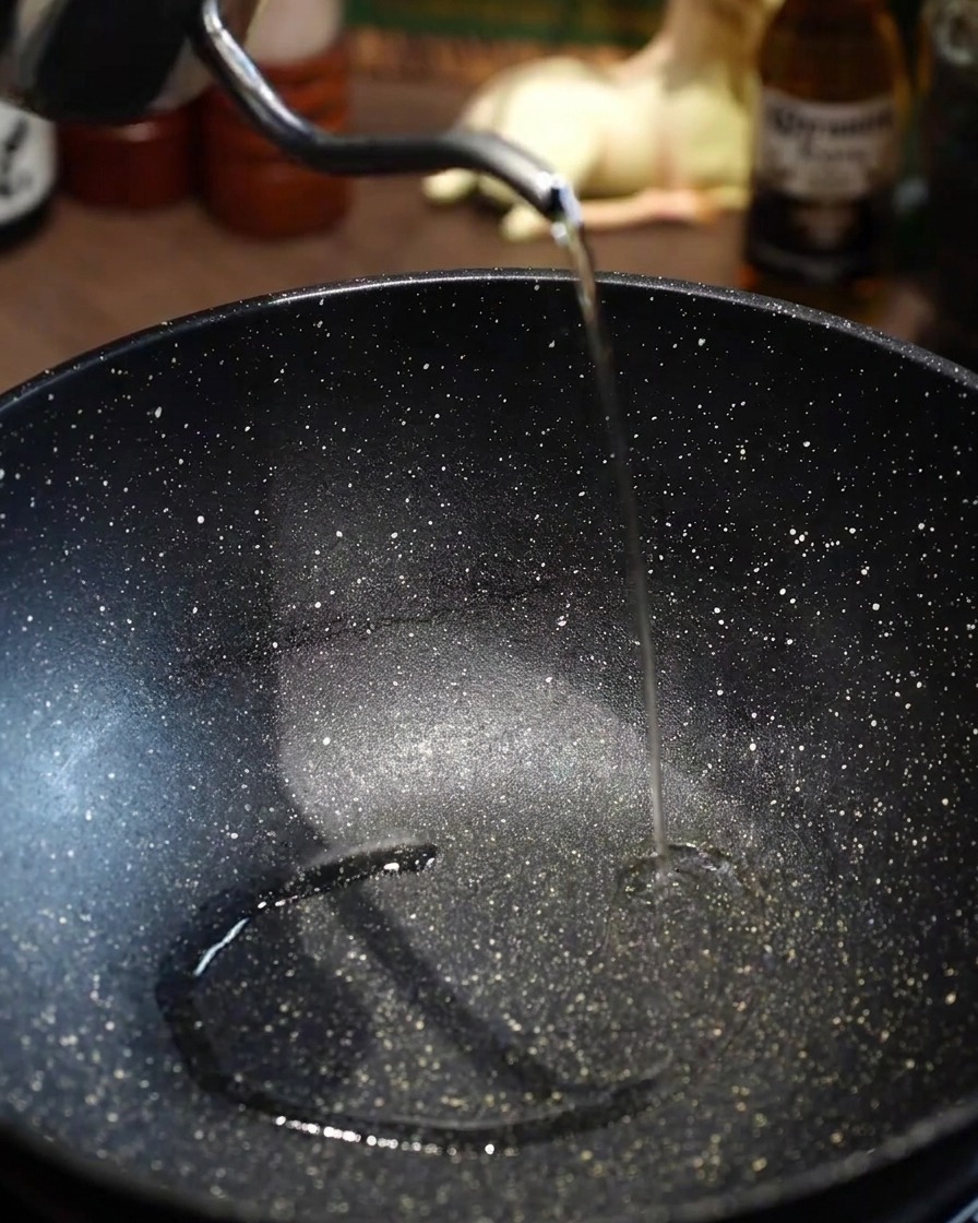Huile de cuisson versée dans une poêle noire vide et préchauffée.