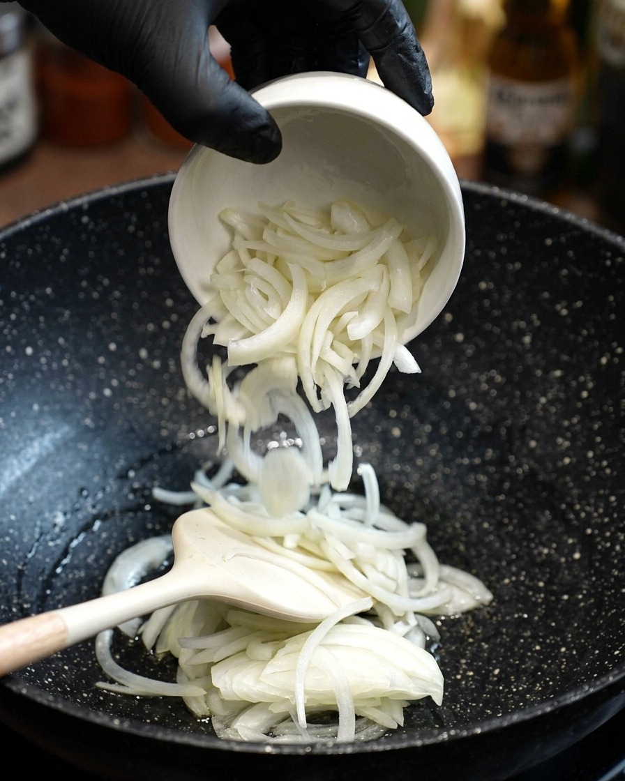 Oignons blancs frais émincés ajoutés dans une poêle avec de lhuile chaude et remués avec une spatule.