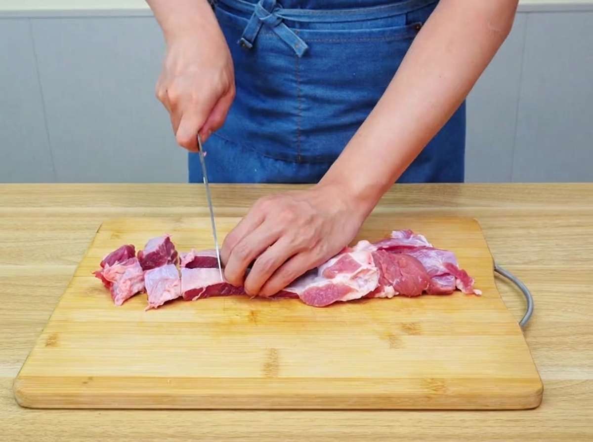 Du bœuf brisket cru coupé en gros morceaux uniformes sur une planche à découper en bois.