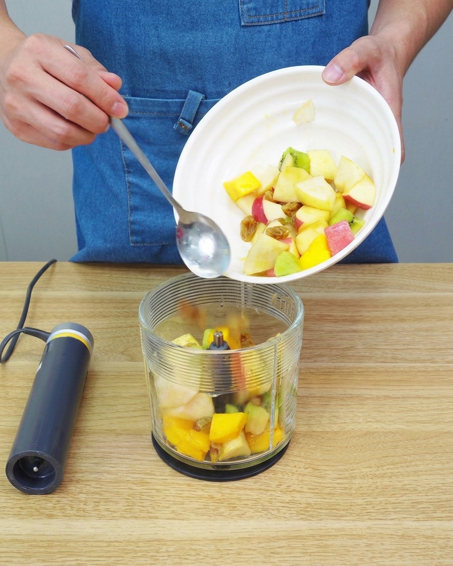 Gros plan sur des morceaux de fruits transformés en une purée épaisse et lisse à lintérieur dun récipient de mixeur.