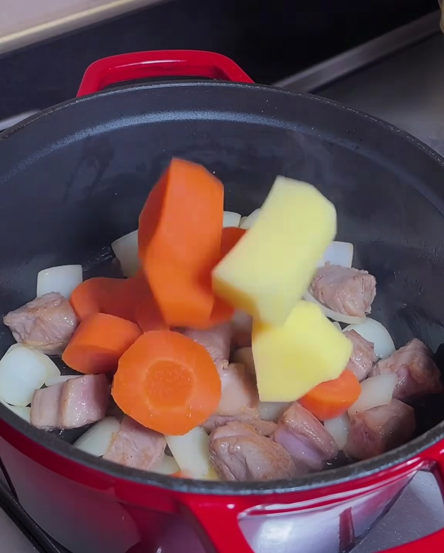 Carottes et pommes de terre mélangées dans la casserole avec le bœuf doré.