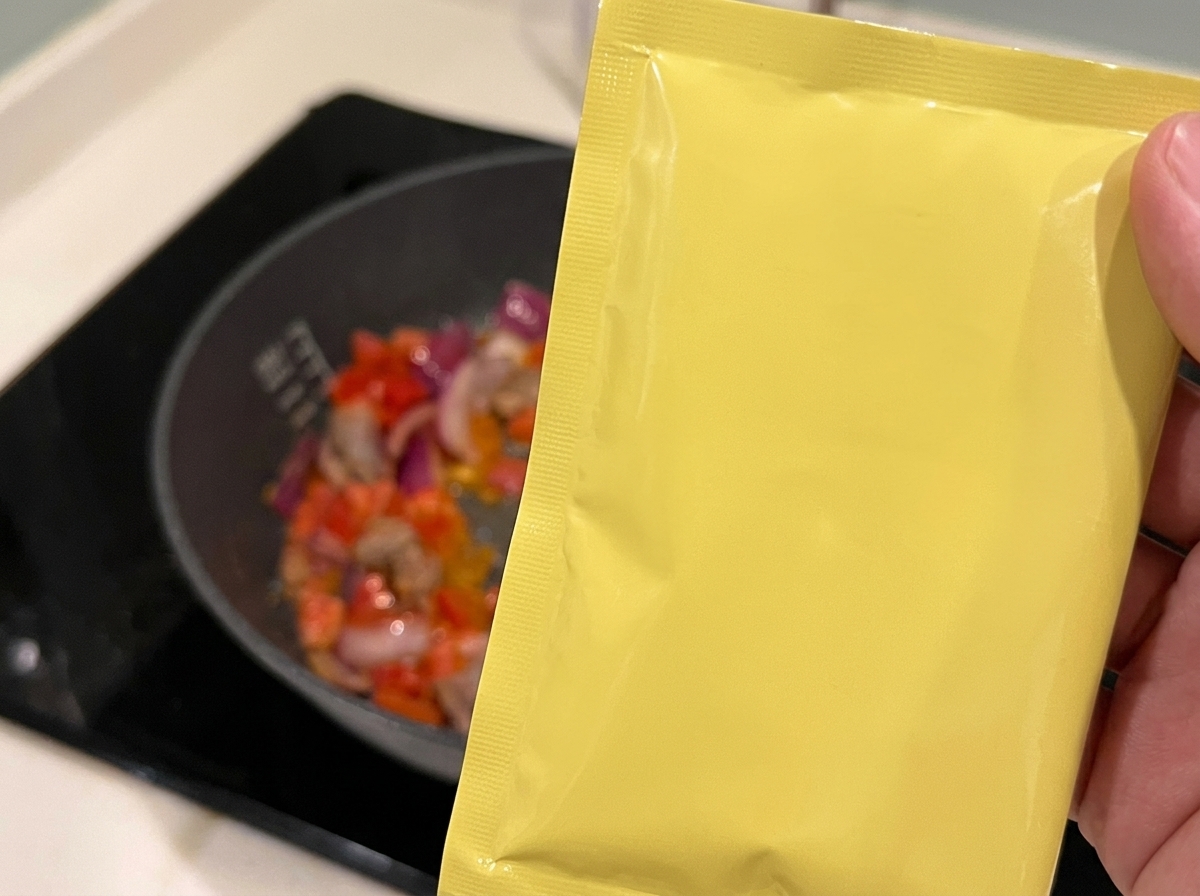 Vin de cuisine versé sur un mélange de bœuf, tomates et oignons dans une poêle.