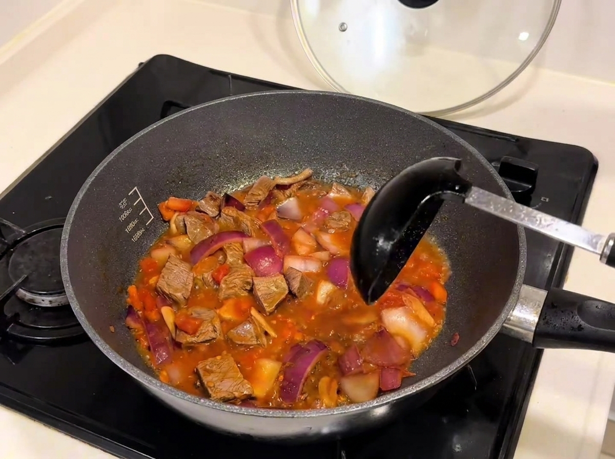 Eau chaude versée dune bouilloire dans une poêle remplie de bœuf et de légumes.