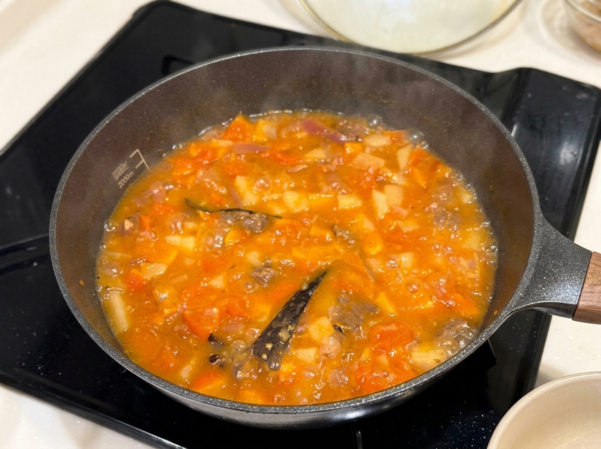 Tablettes de curry solides placées dans une poêle de ragoût frémissant.
