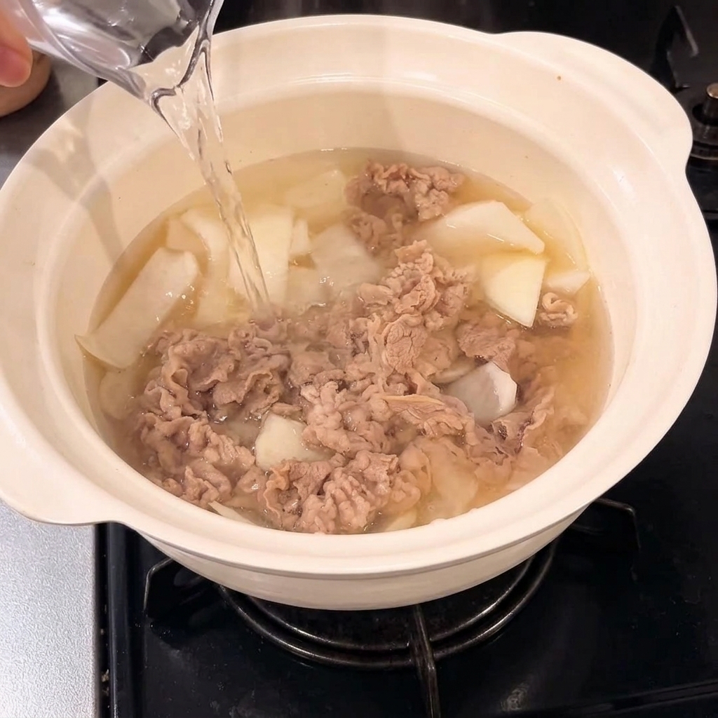 De leau versée dans la casserole contenant le mélange de bœuf et doignons.