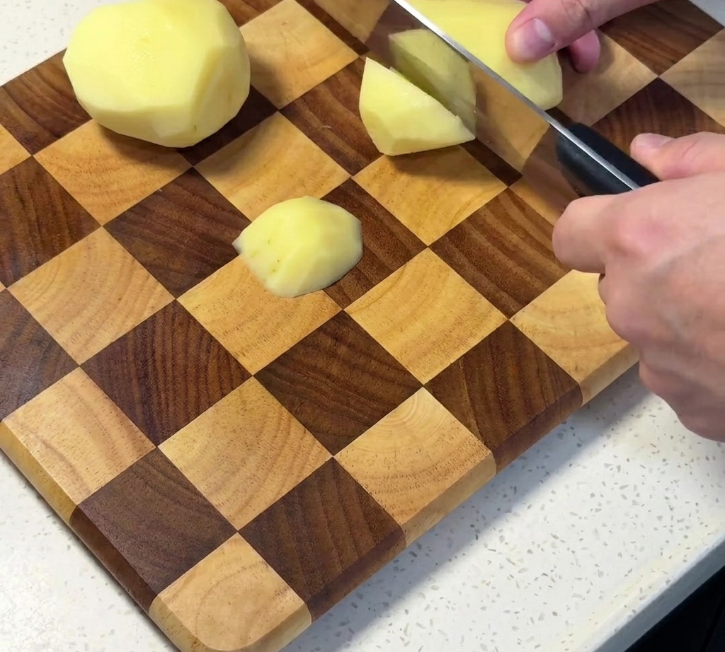 Pommes de terre crues épluchées et coupées en dés sur une planche à découper.