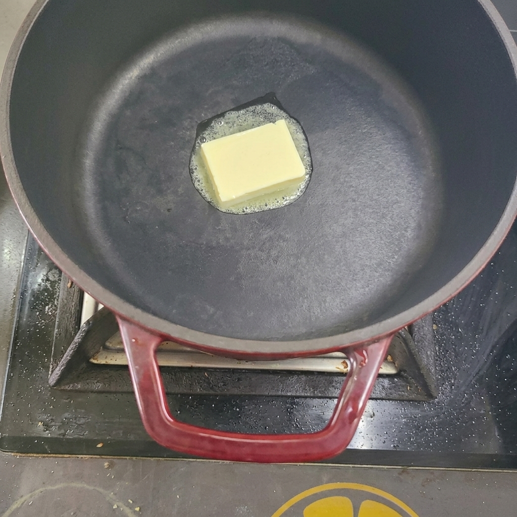 Un cube de beurre fondant dans une marmite sur la cuisinière.