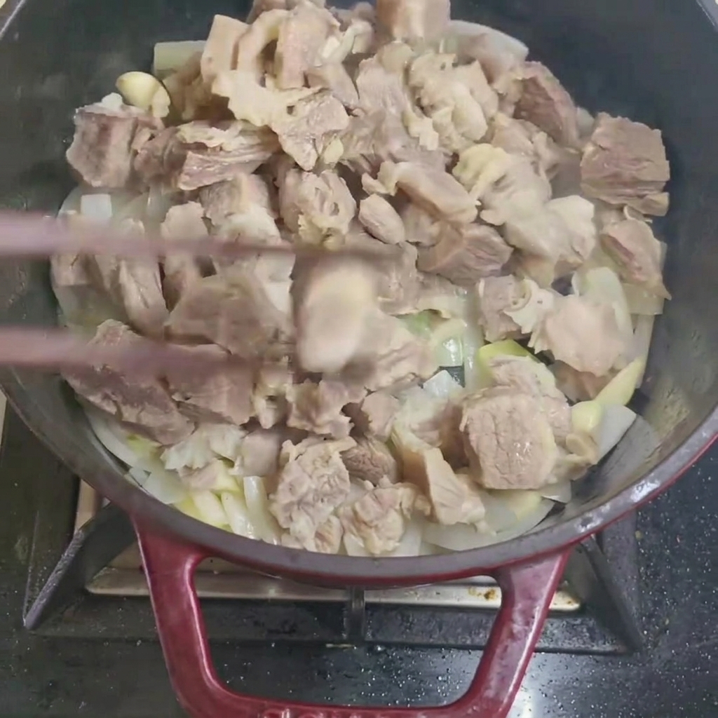 Mélanger des morceaux de bœuf blanchis avec des oignons et de lail dans une casserole.