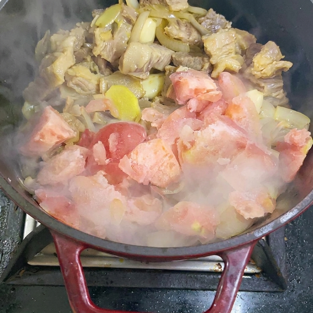 Ajout de morceaux de tomates surgelées dans la poêle.