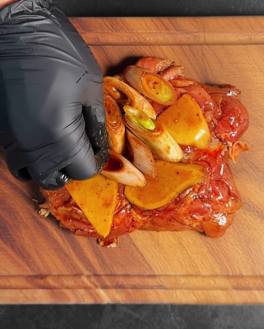 Morceaux de poulet enrobés de marinade et daromates dans un bol en métal.