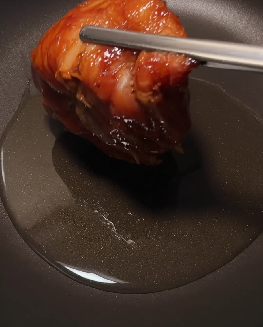 Cuisses de poulet en train de frire dans une poêle, peau croustillante visible.