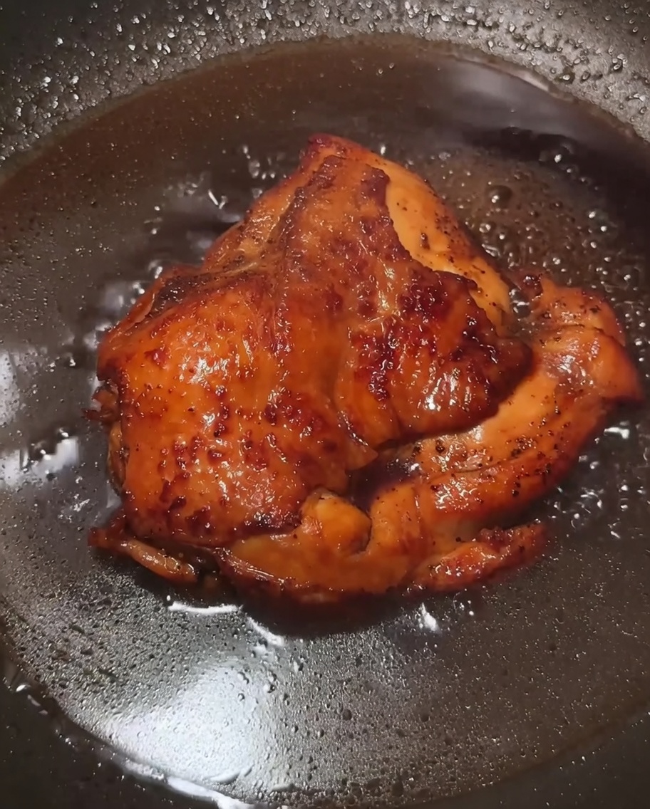 Sauce brune brillante et épaisse nappant le poulet dans la poêle.