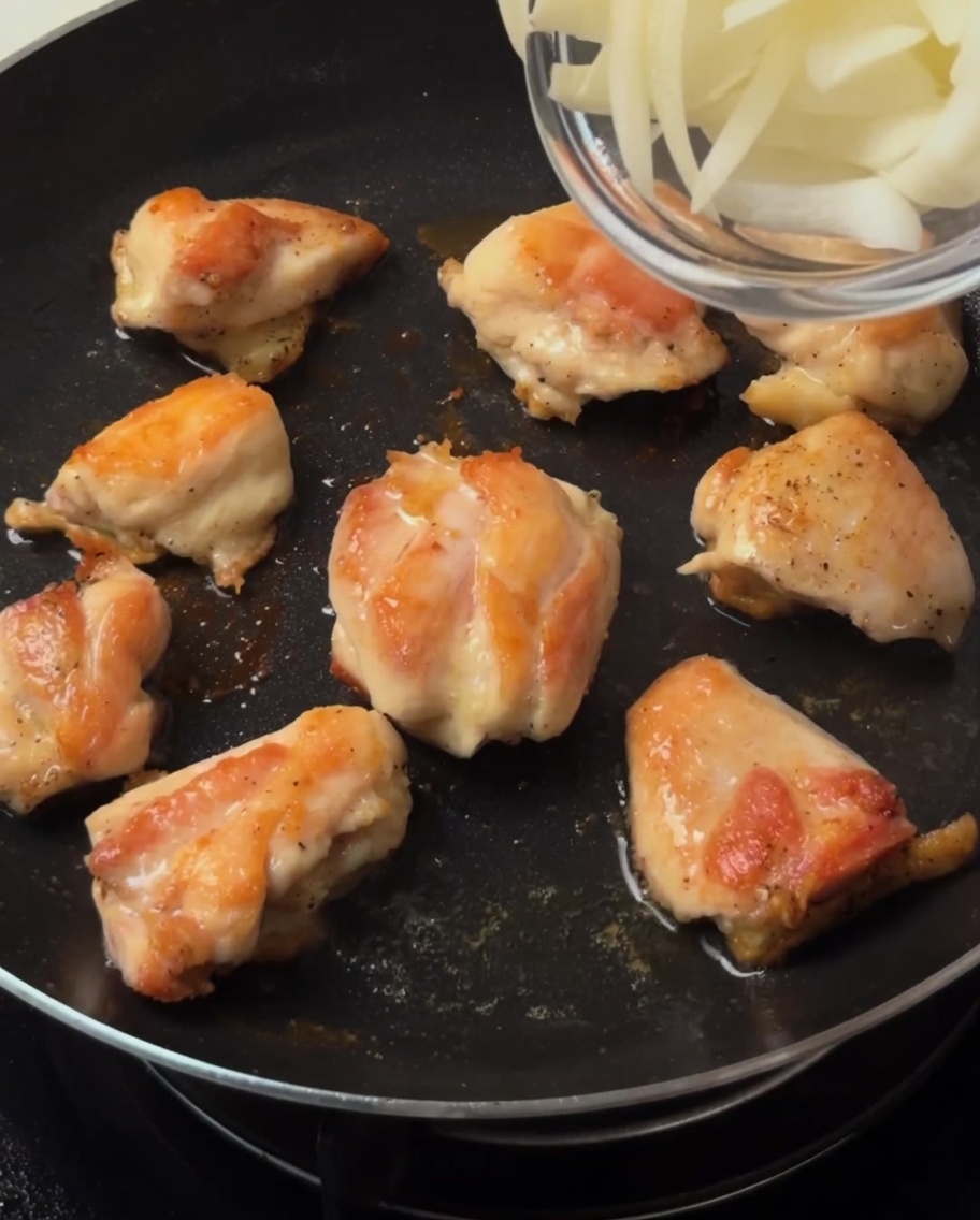 Lamelles doignons ajoutées dans la poêle avec le poulet doré.