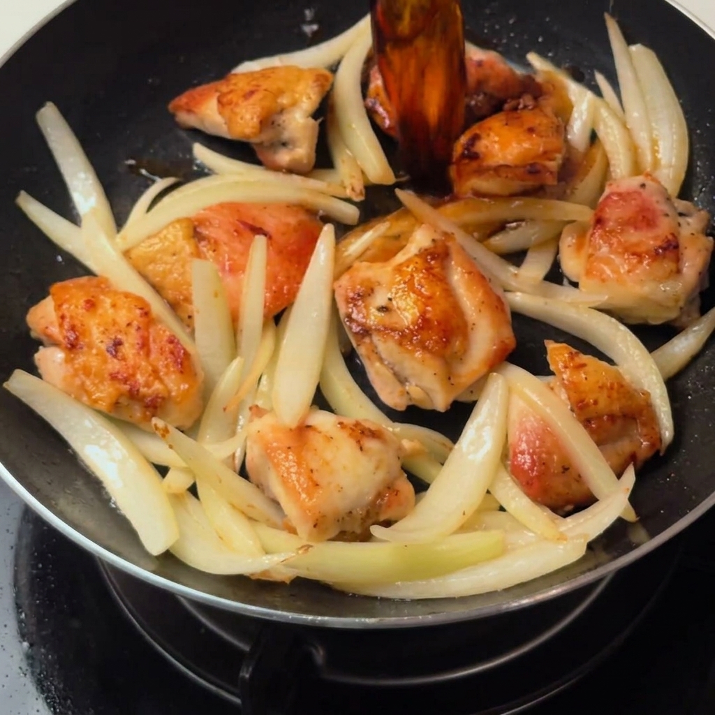 Le poulet et les oignons mijotant dans la sauce au dashi dans la poêle.