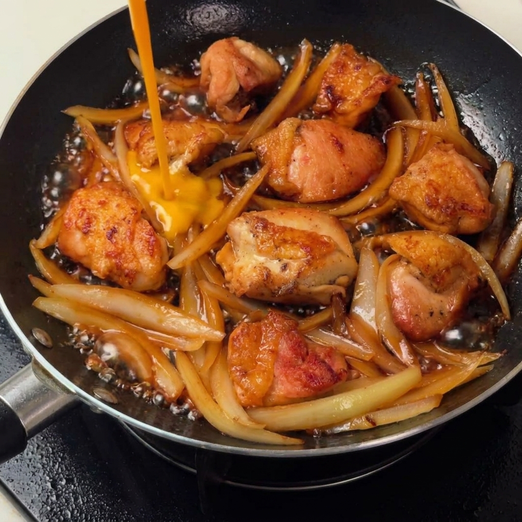 Œufs battus versés sur le mélange de poulet et doignons pour créer une nappe légère.