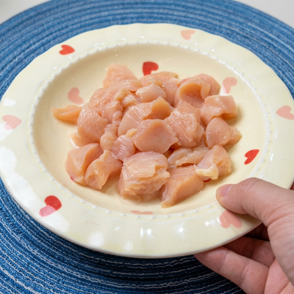 Dés de blanc de poulet crus dans un bol, assaisonnés avec de la sauce soja, du vin et des épices.