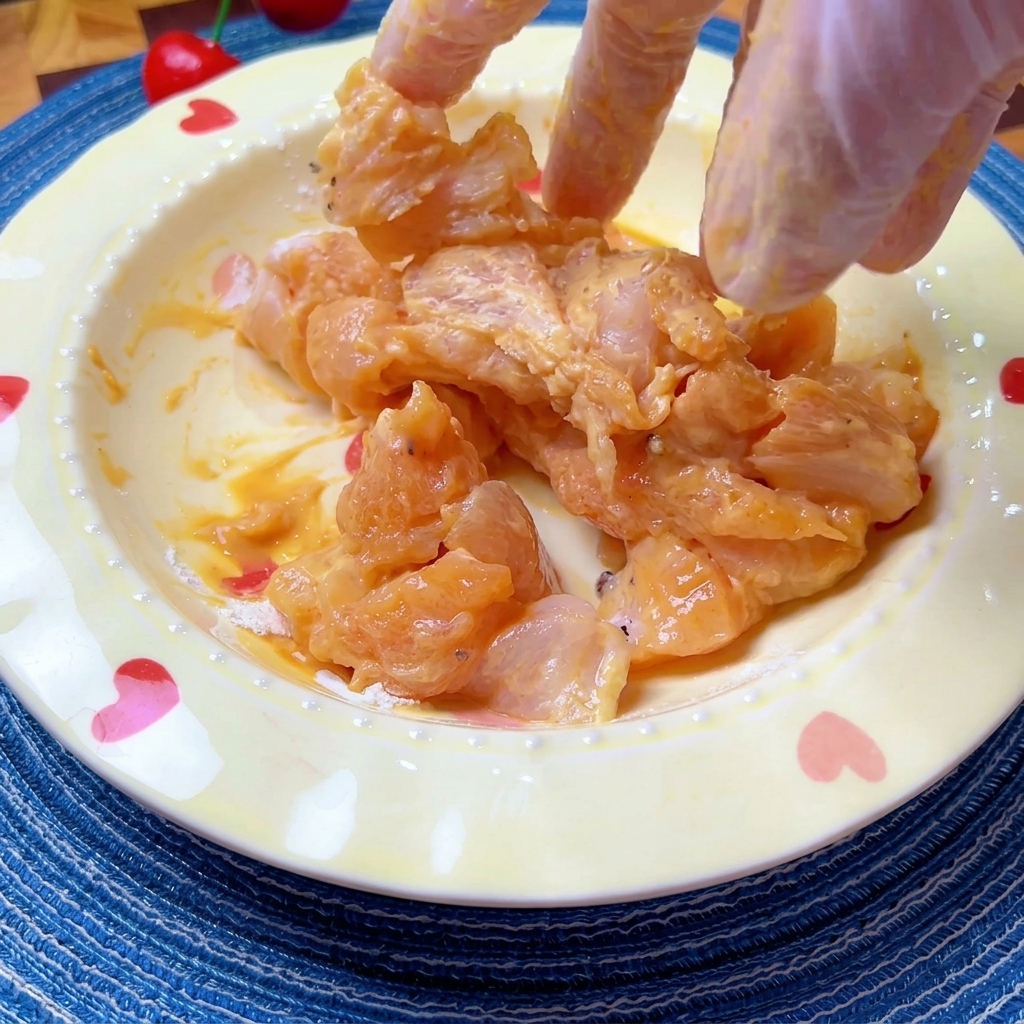 Morceaux de poulet marinés mélangés à la main dans un bol.
