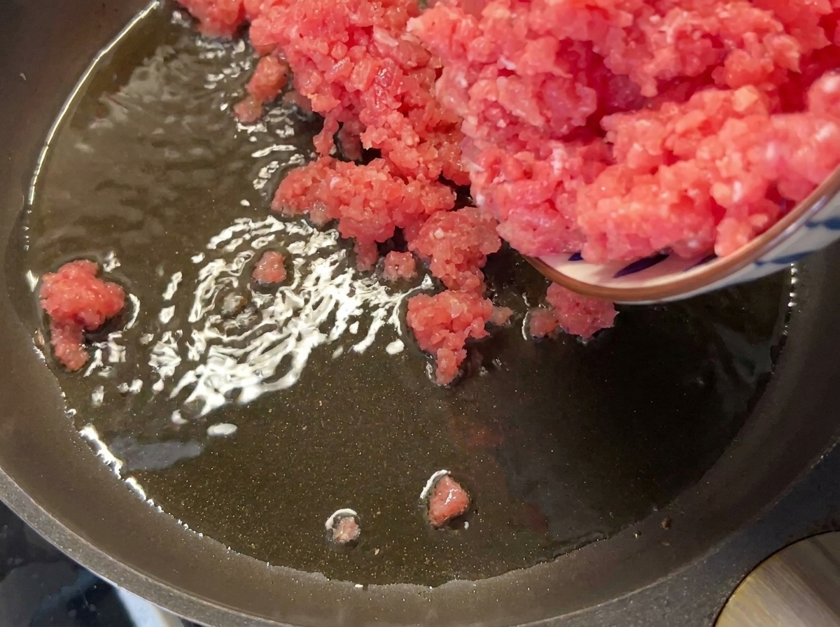 Porc maigre haché ajouté dans une poêle chaude huilée.