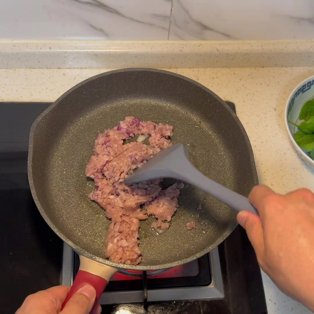 Mélange de viande hachée et doignon en train de dorer dans une poêle.