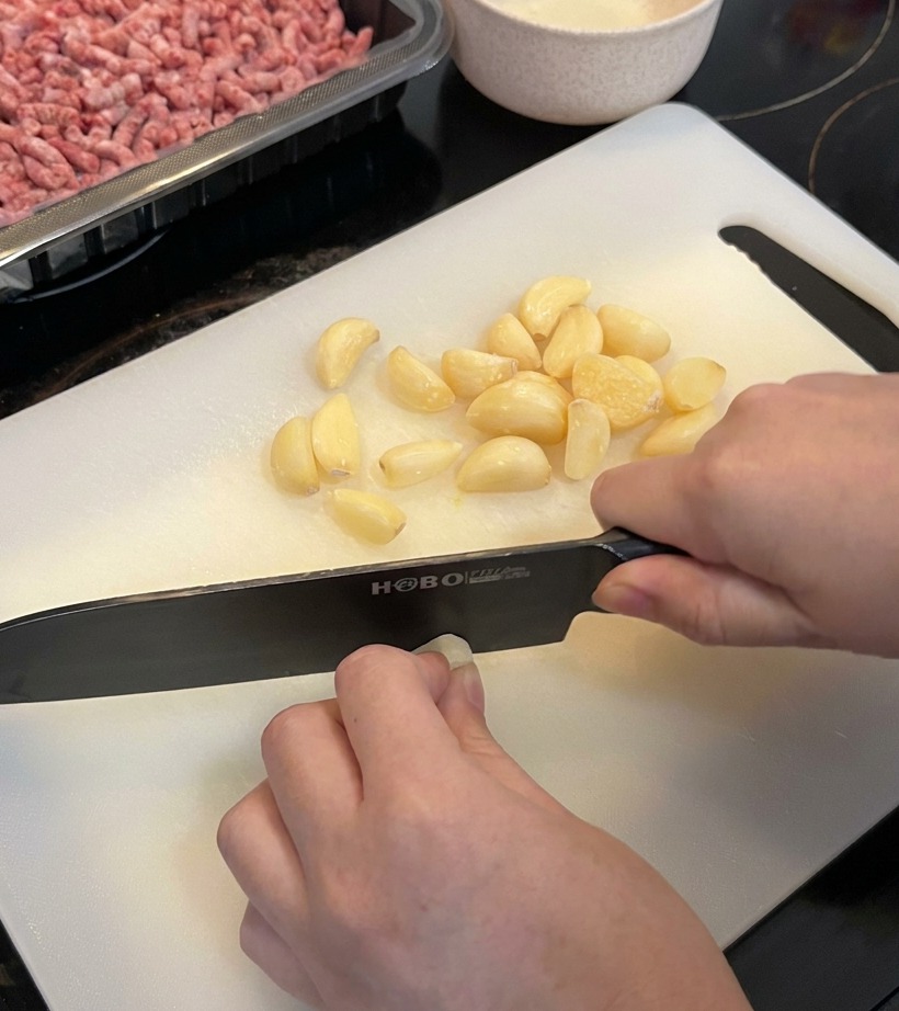 Gros plan sur un tas de gousses dail frais hachées sur une planche à découper propre.