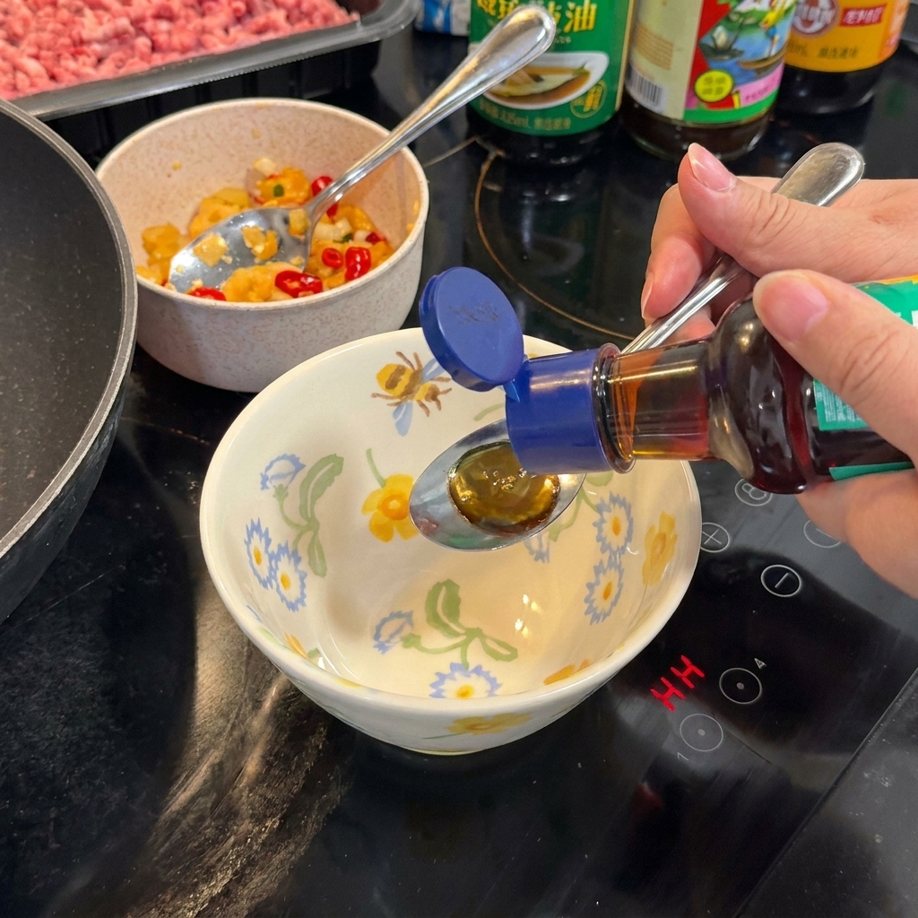 Cuillère mélangeant une sauce sombre dans un bol à motifs sur la cuisinière.
