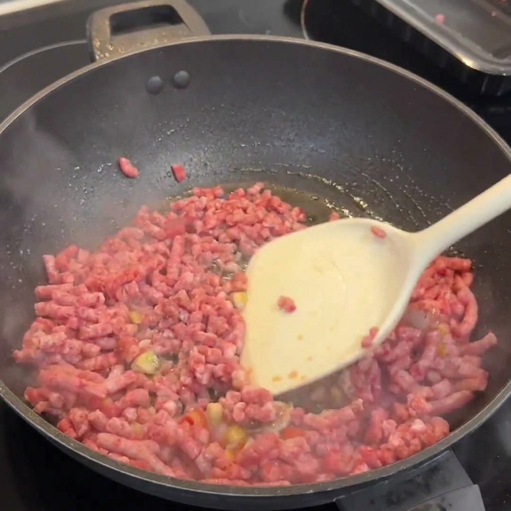 Le bœuf Wagyu bruni dans le wok, en cours démiettement avec une spatule blanche.