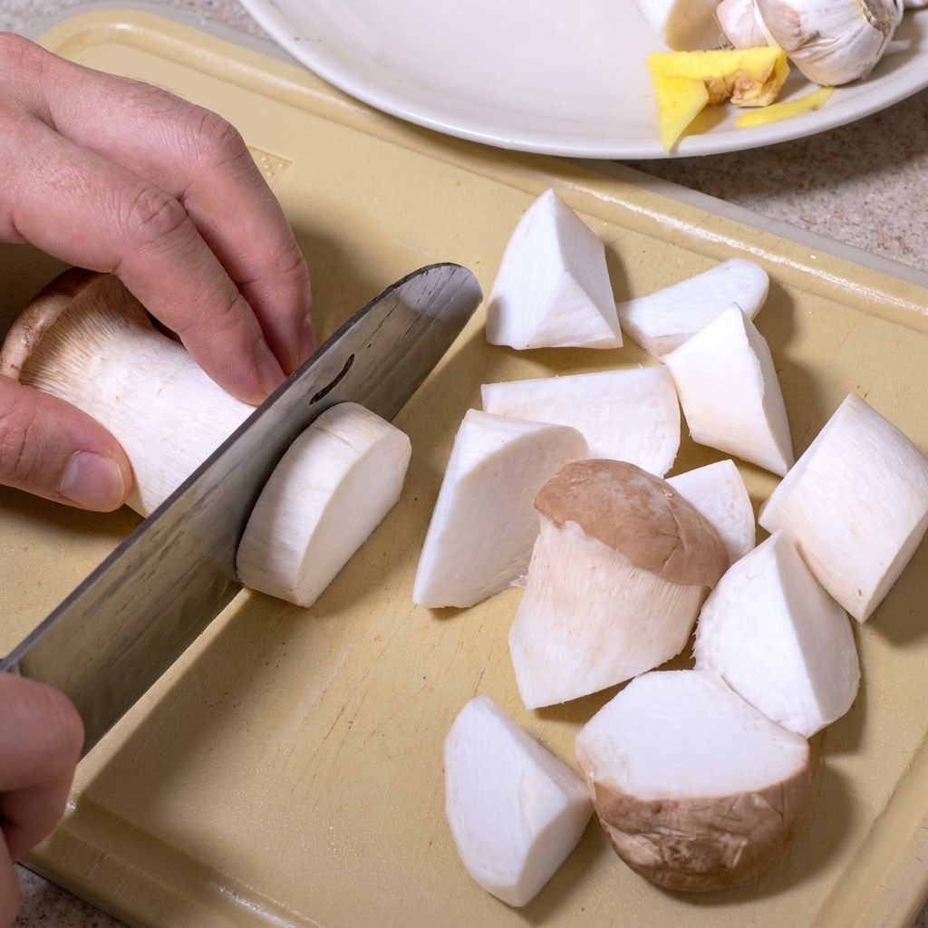 Pleurotes découpés en morceaux irréguliers sur une planche à découper beige.
