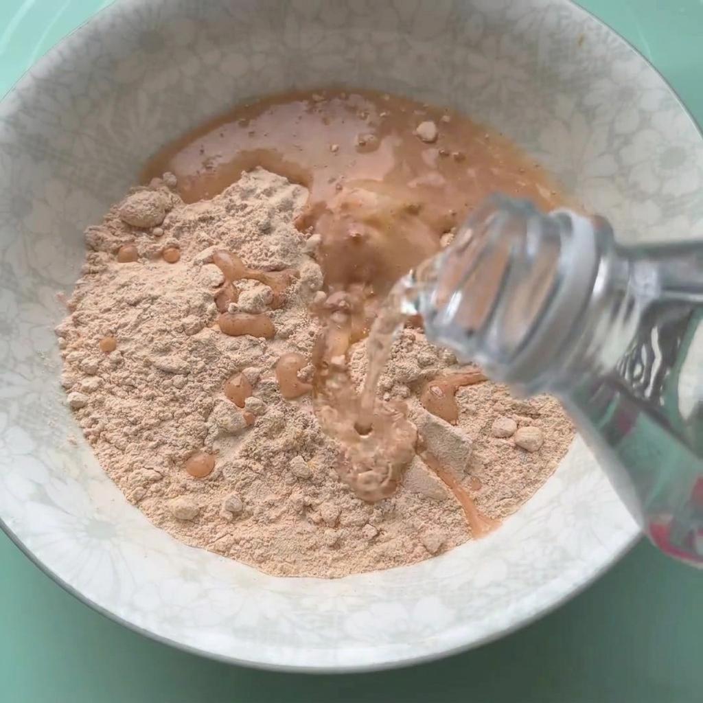 De la préparation pour poulet frit mélangée avec de leau dans un bol blanc.