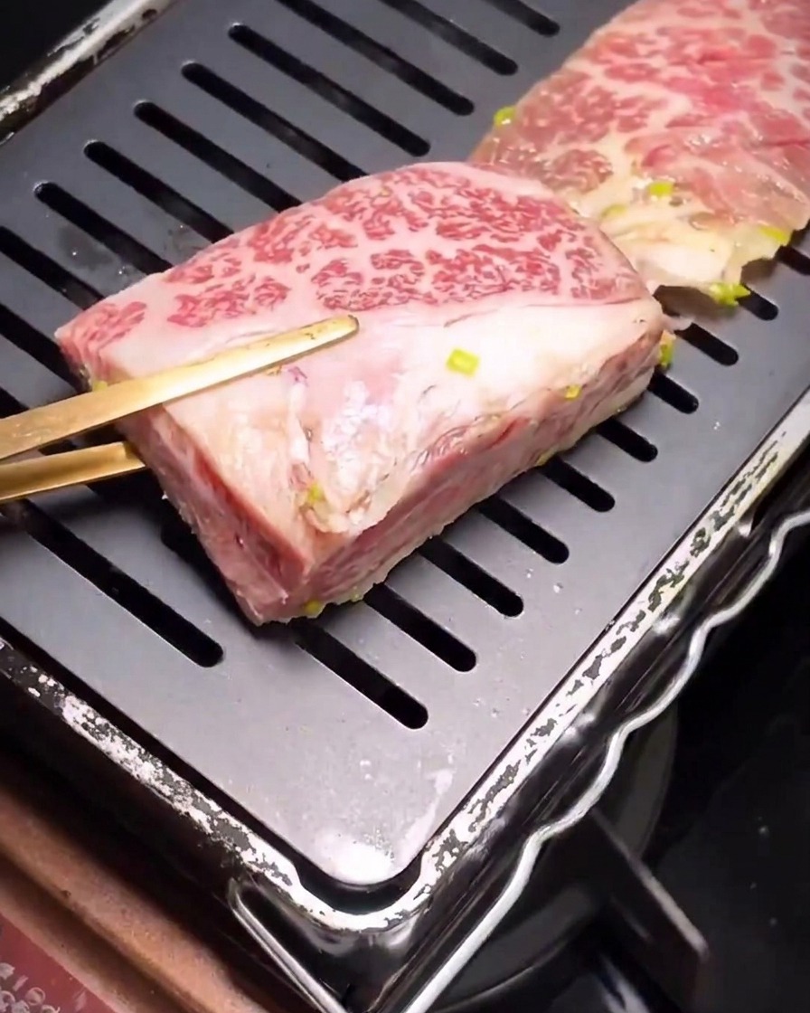 Des côtes de bœuf marinées commençant à saisir sur une poêle à griller noire striée bien chaude.