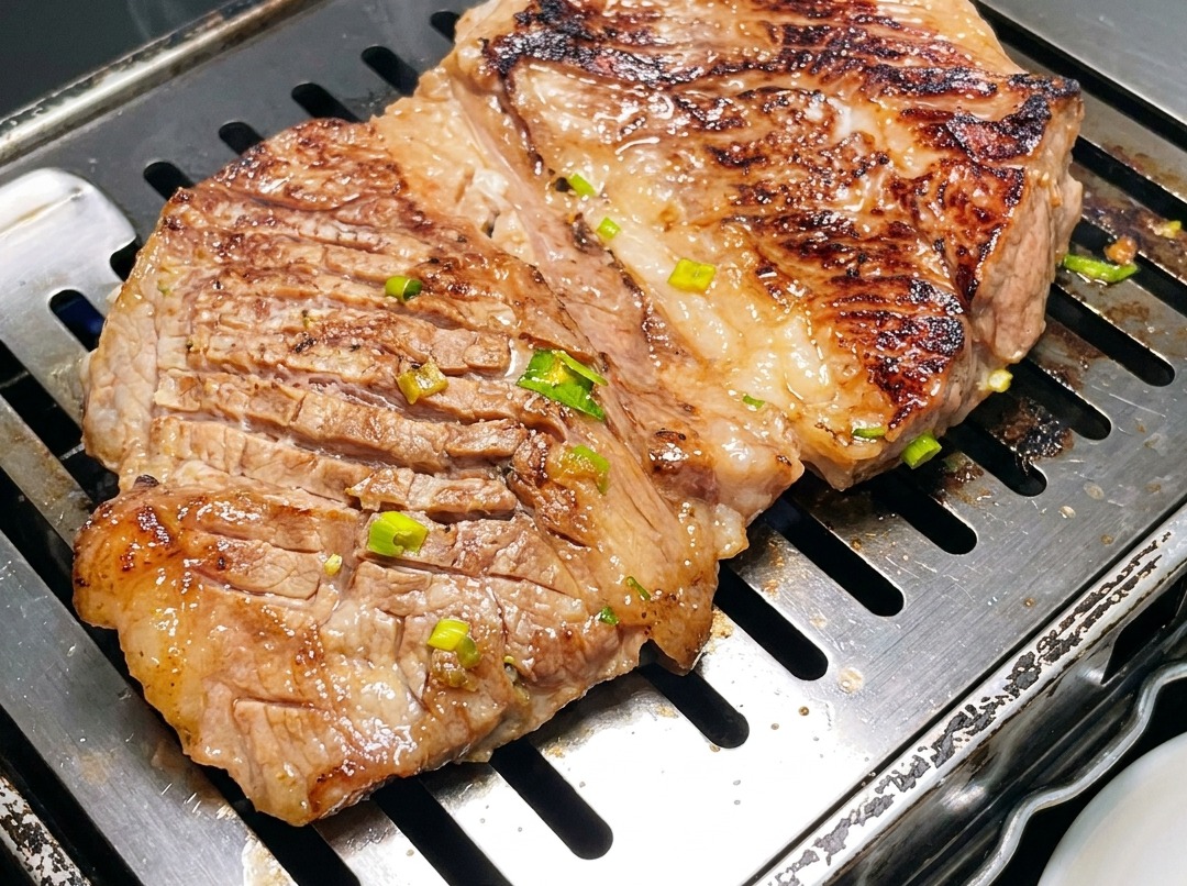 Gros plan sur des côtes de bœuf grillées découpées en plus petits morceaux avec des ciseaux sur une poêle chaude.