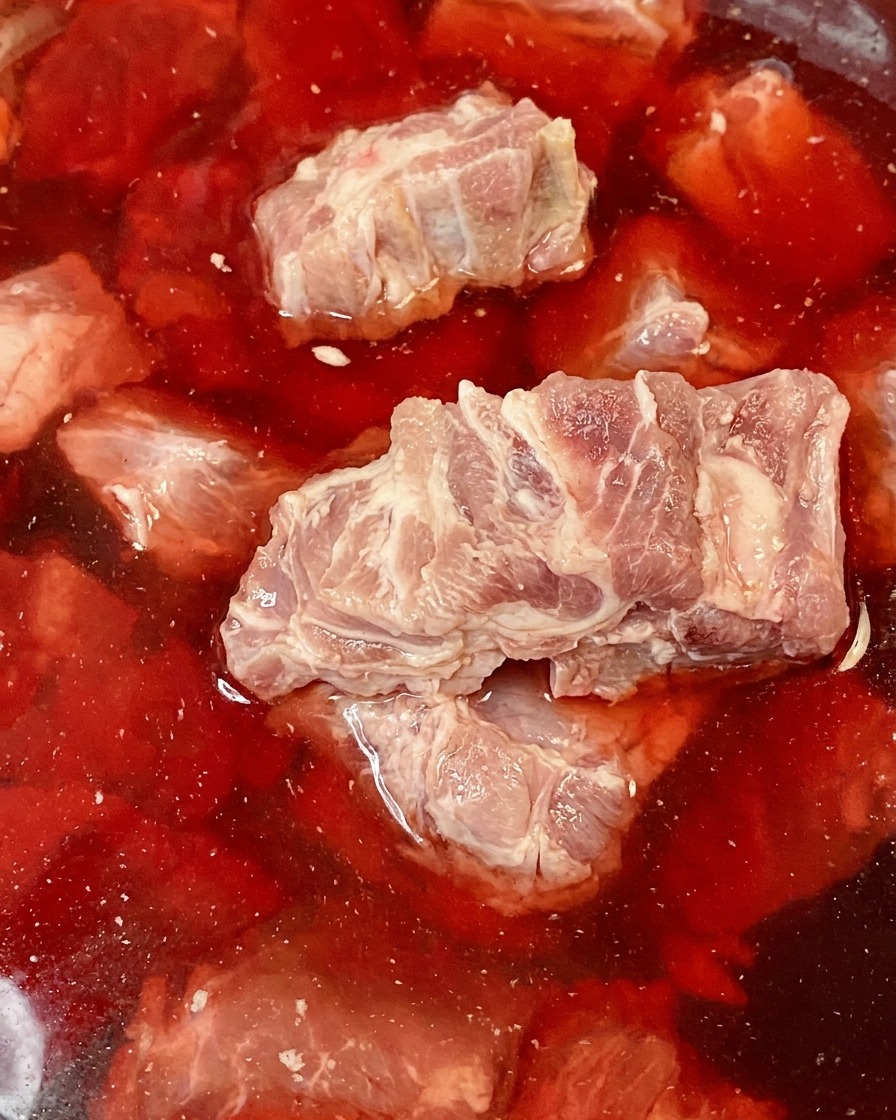 Os déchine de porc crus immergés dans un bol deau rouge légèrement teintée de sang.