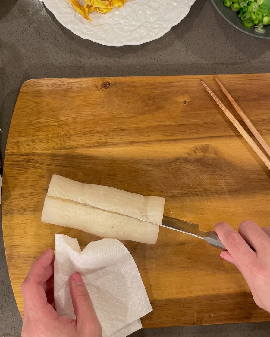 Radis blanc cuit tranché en petits rectangles sur une planche en bois.