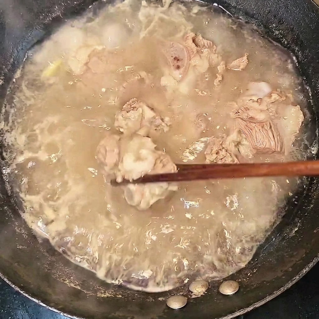 Travers de bœuf blanchis retirés de leau bouillante avec des baguettes.