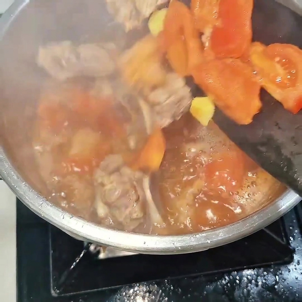 Le mélange de travers de bœuf et de tomates versé dans un autocuiseur en acier, prêt à être scellé.