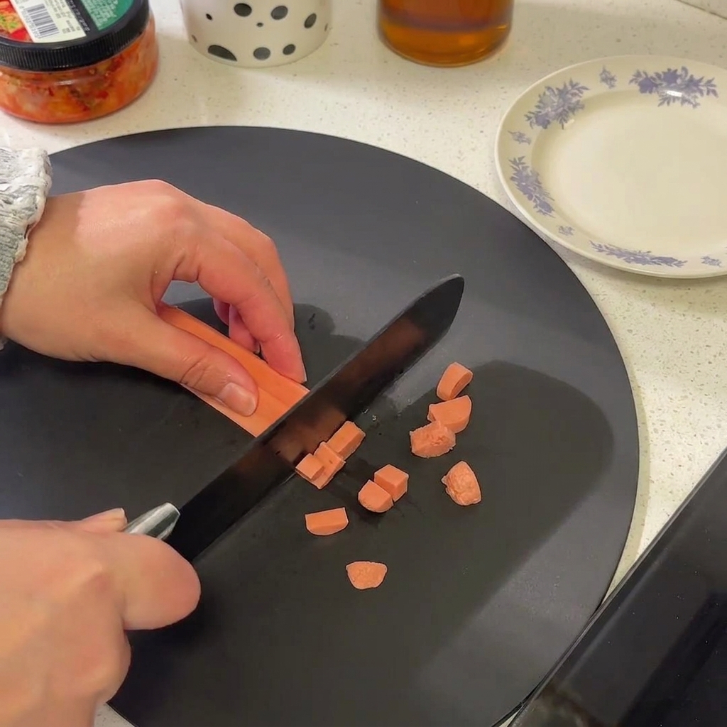 Gros plan dune saucisse coupée en petites rondelles sur une planche à découper noire.