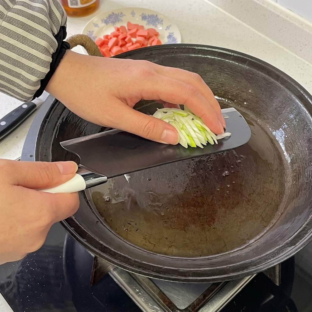 Des rondelles de saucisse et des oignons verts grésillant dans une poêle chaude.