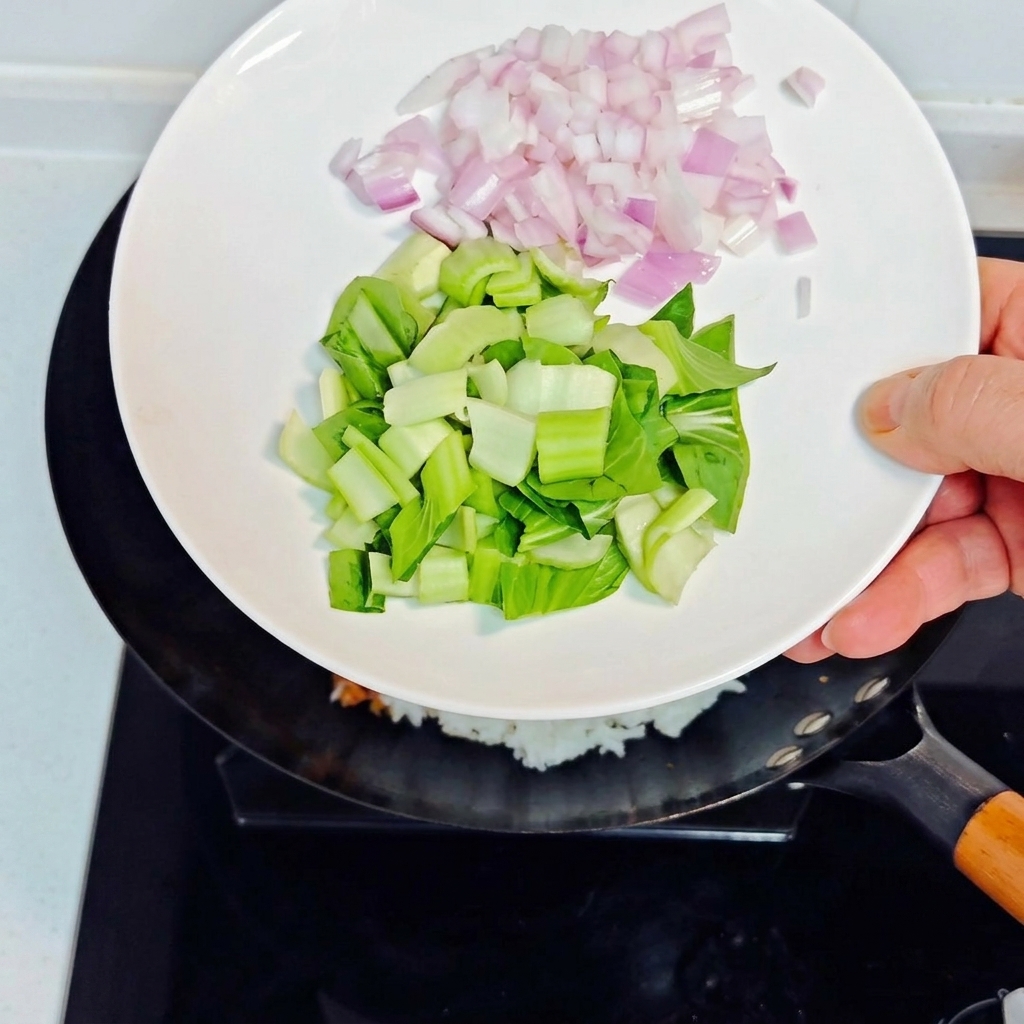 Ajout doignons violets en dés et de bok choy haché dans le wok avec le riz sauté.