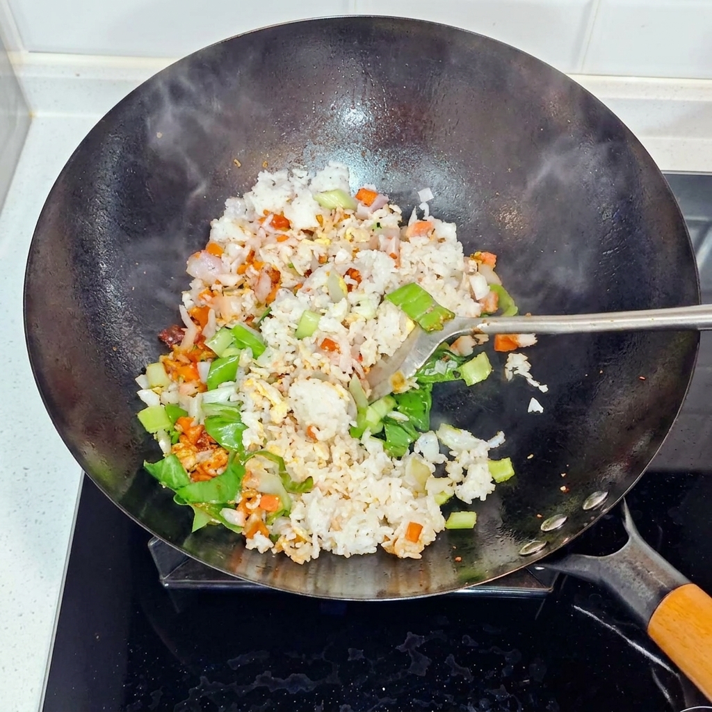 Riz, oignons et bok choy mélangés et sautés dans un wok.