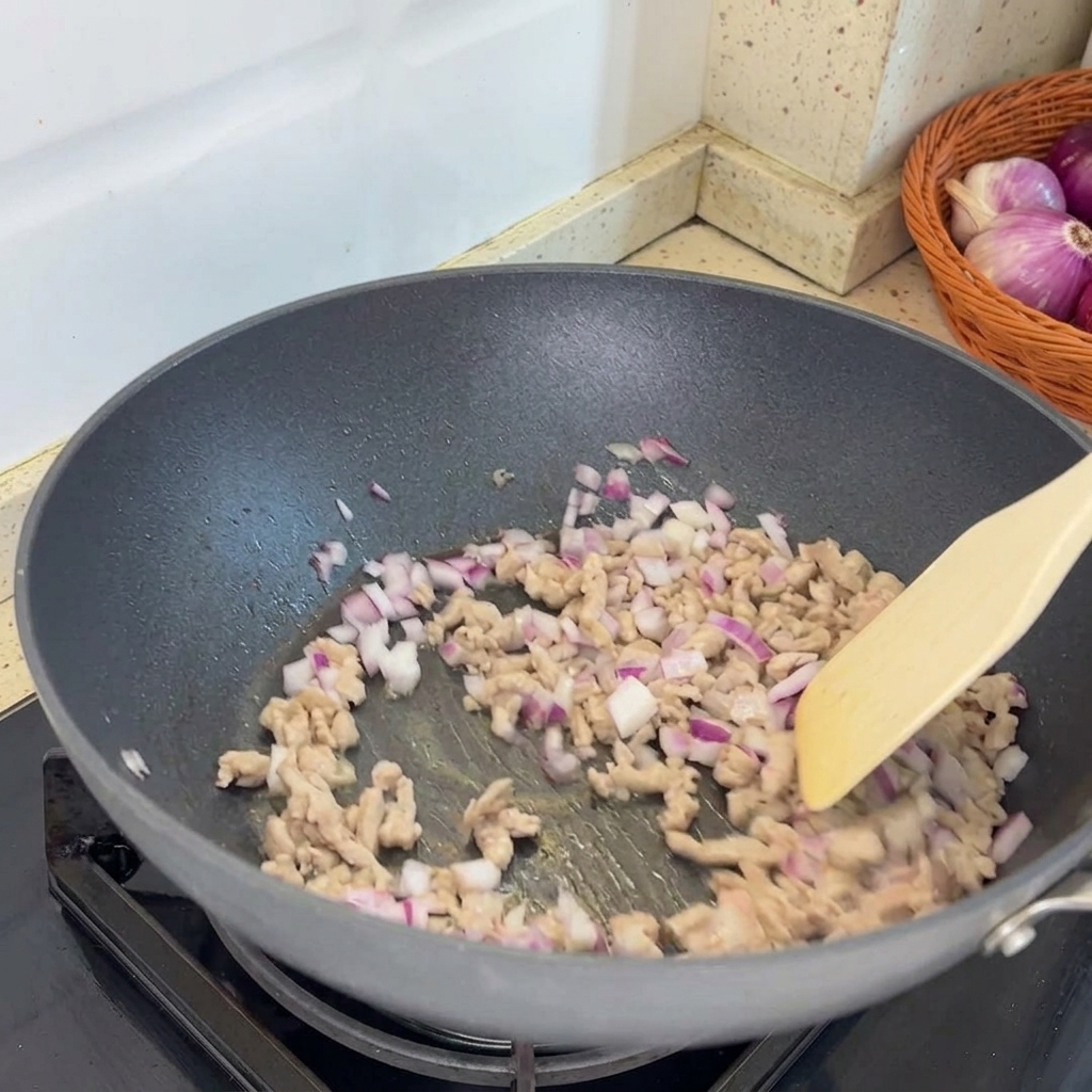 Échalotes hachées ajoutées à la poêle et mélangées au porc haché cuit.