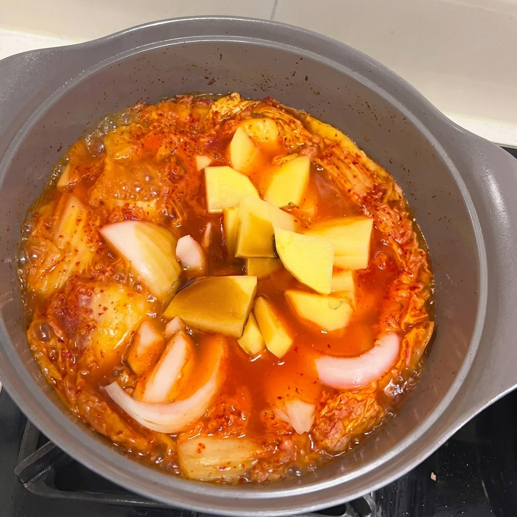 Morceaux doignon et de pomme de terre ajoutés au ragoût bouillonnant.