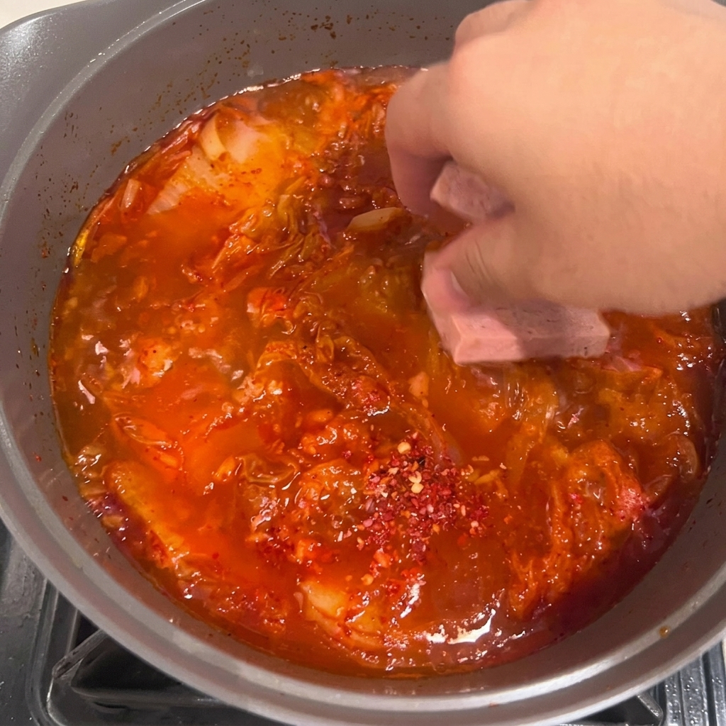 Tranches de tofu soigneusement placées dans le ragoût rouge bouillonnant.