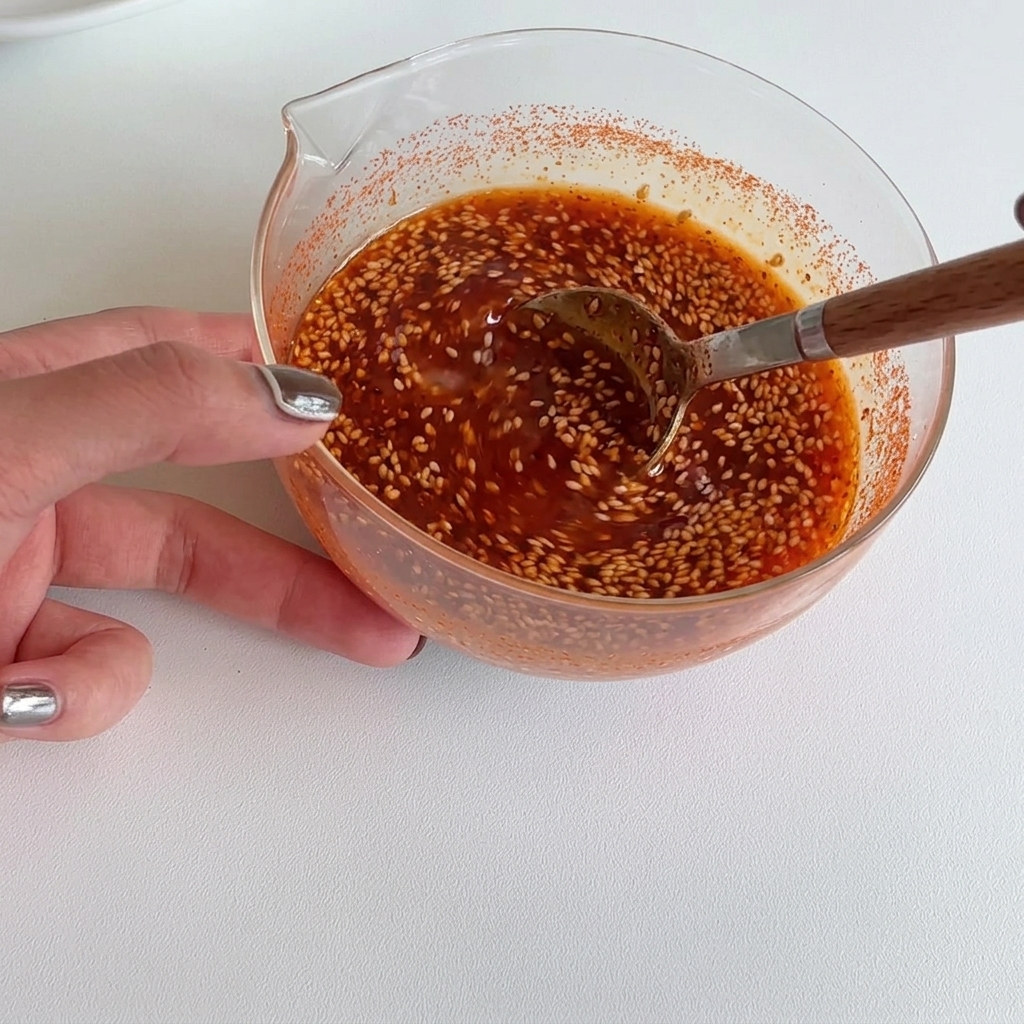 Mélange dune sauce rouge vive dans un bol à laide dune cuillère en bois.